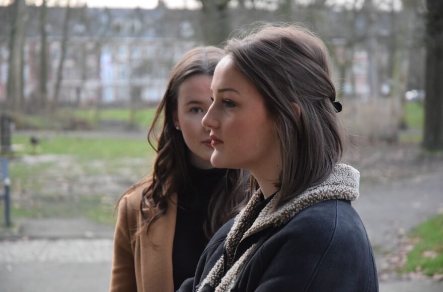 2 vrouwen staan bij elkaar in het park. Hun gezichten overlappen